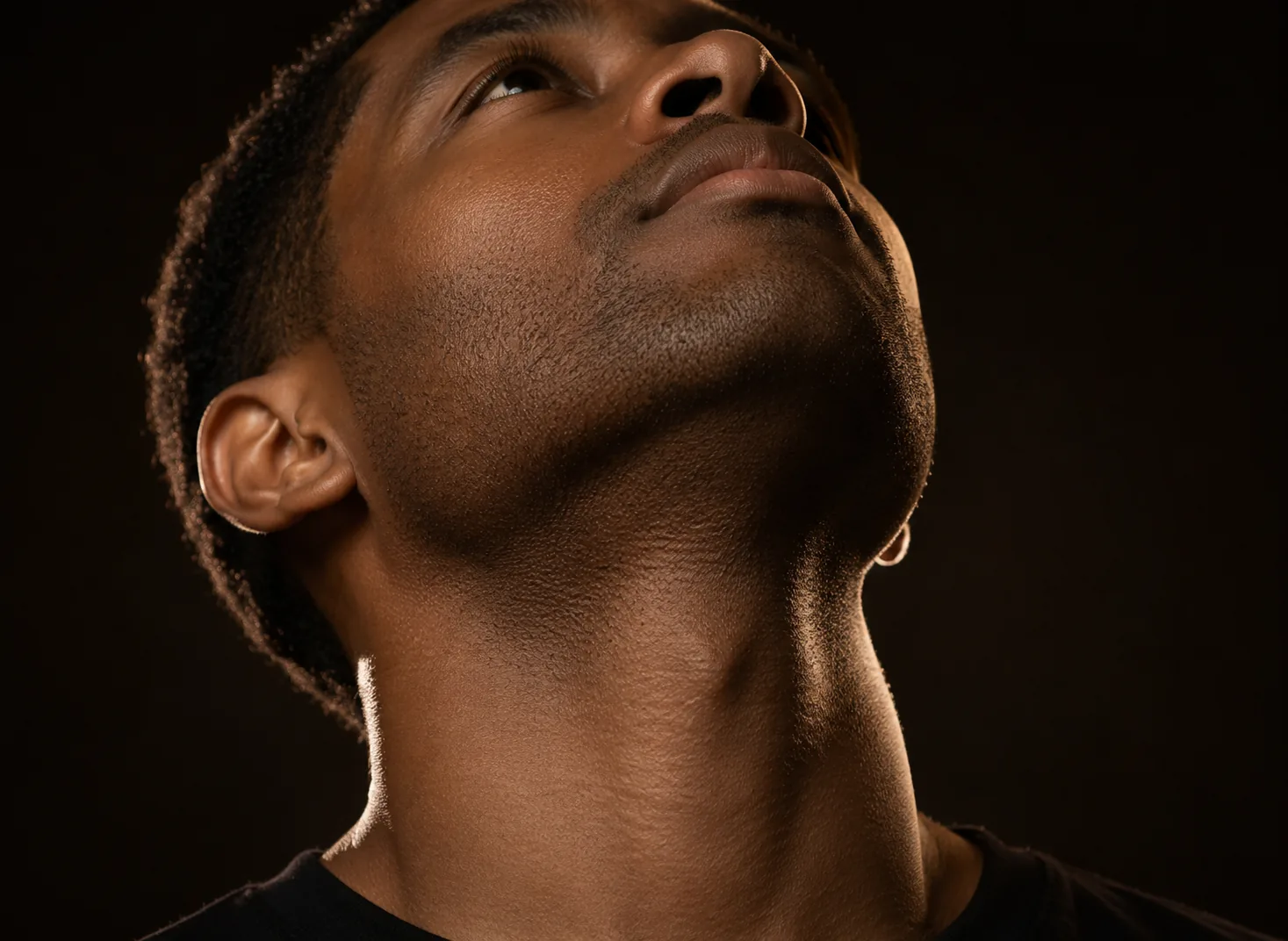 A man's raised chin and neckline in dramatic upward light